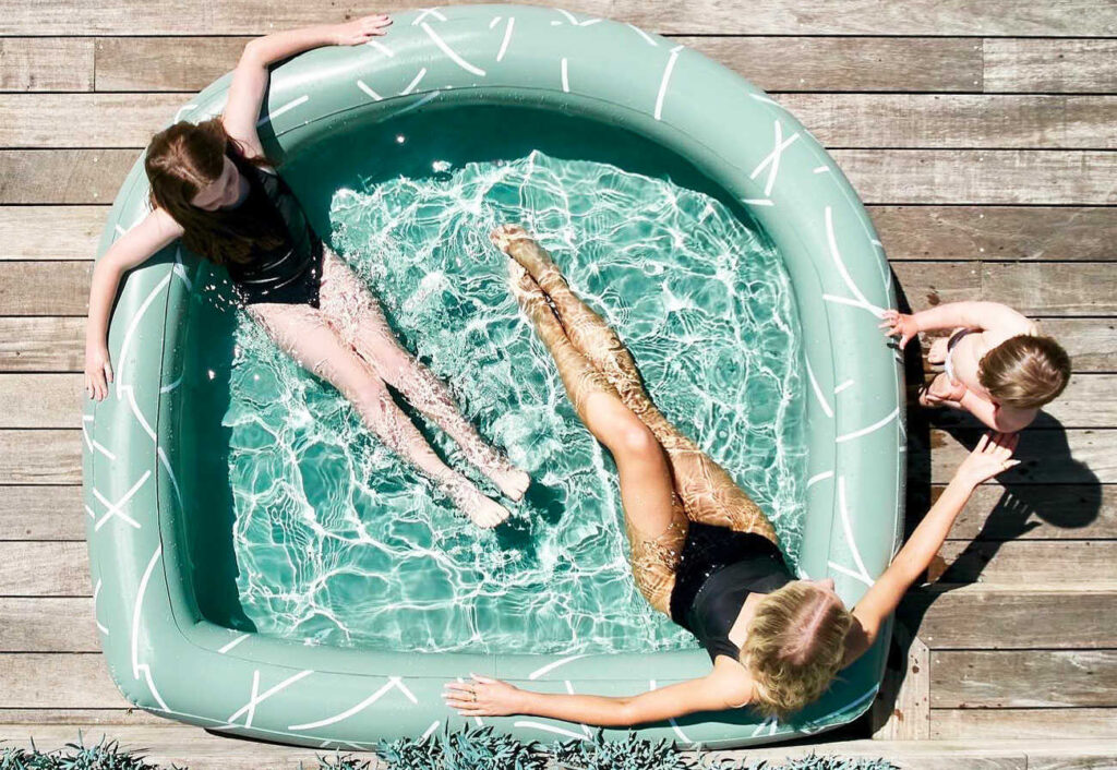 Woman and kids play in an inflatable pool on a timber deck.