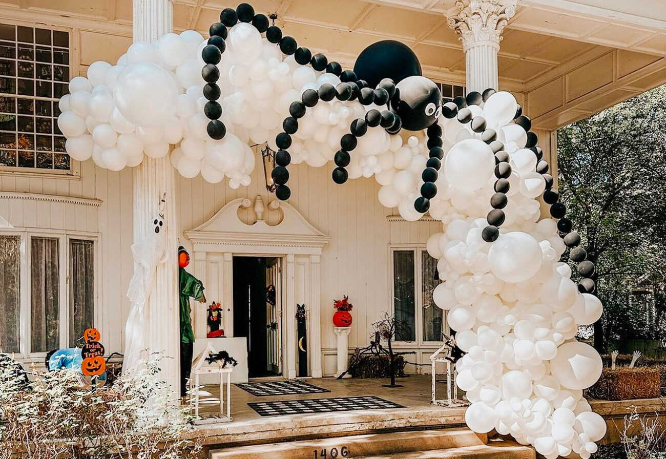 Large house decorated with black and white balloons that look like a spider's web.