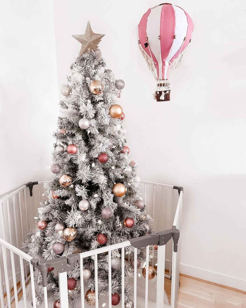 A christmas tree enclosed in a playpen.