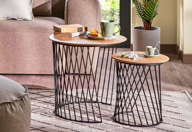 Mixed material side tables on a neutral rug next to a plush sofa.