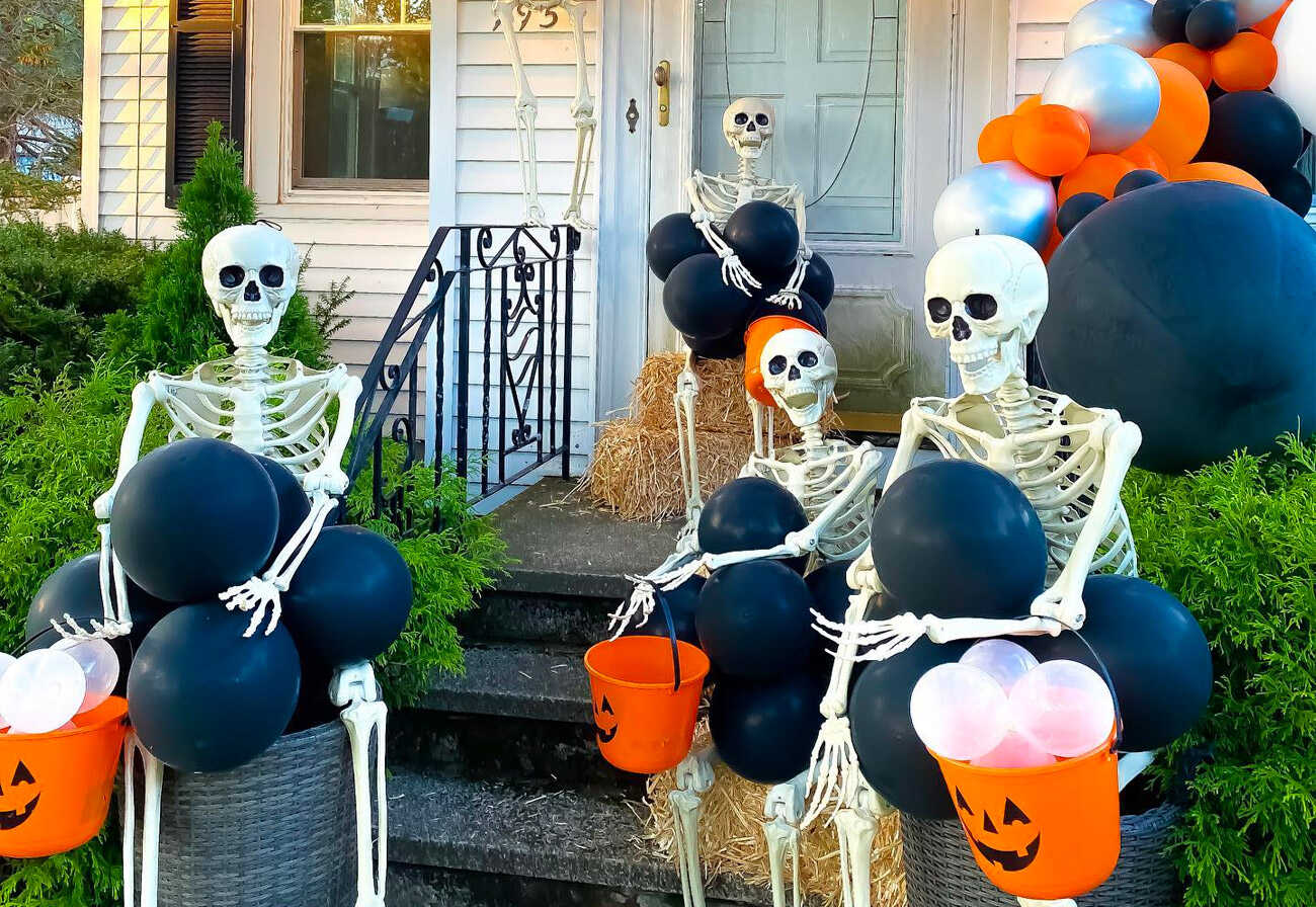 Plastic skeletons sitting on a front porch for Halloween.