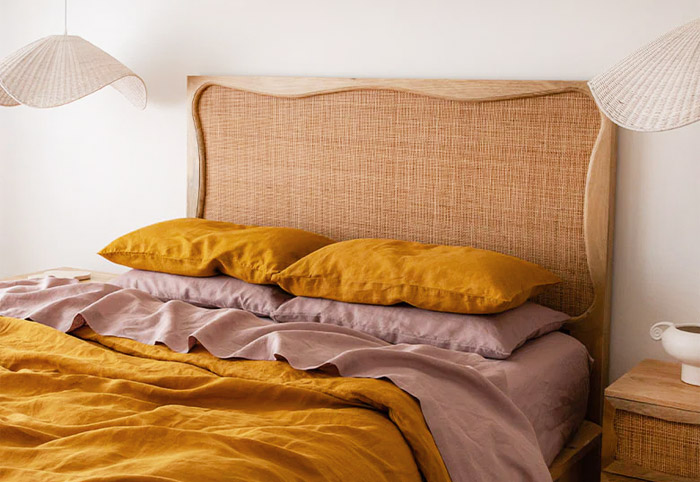 Queen bed with a rattan headboard and mustard coloured linen.