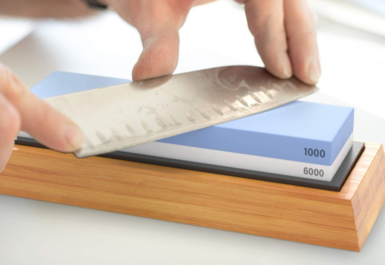 Person sharpening a knife on a whetstone.
