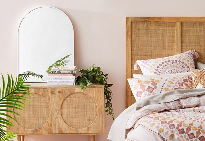 White arched mirror above a cabinet in a bedroom.