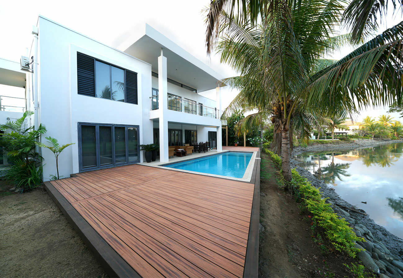 Modern house next to a lake with a swimming pool and deck.