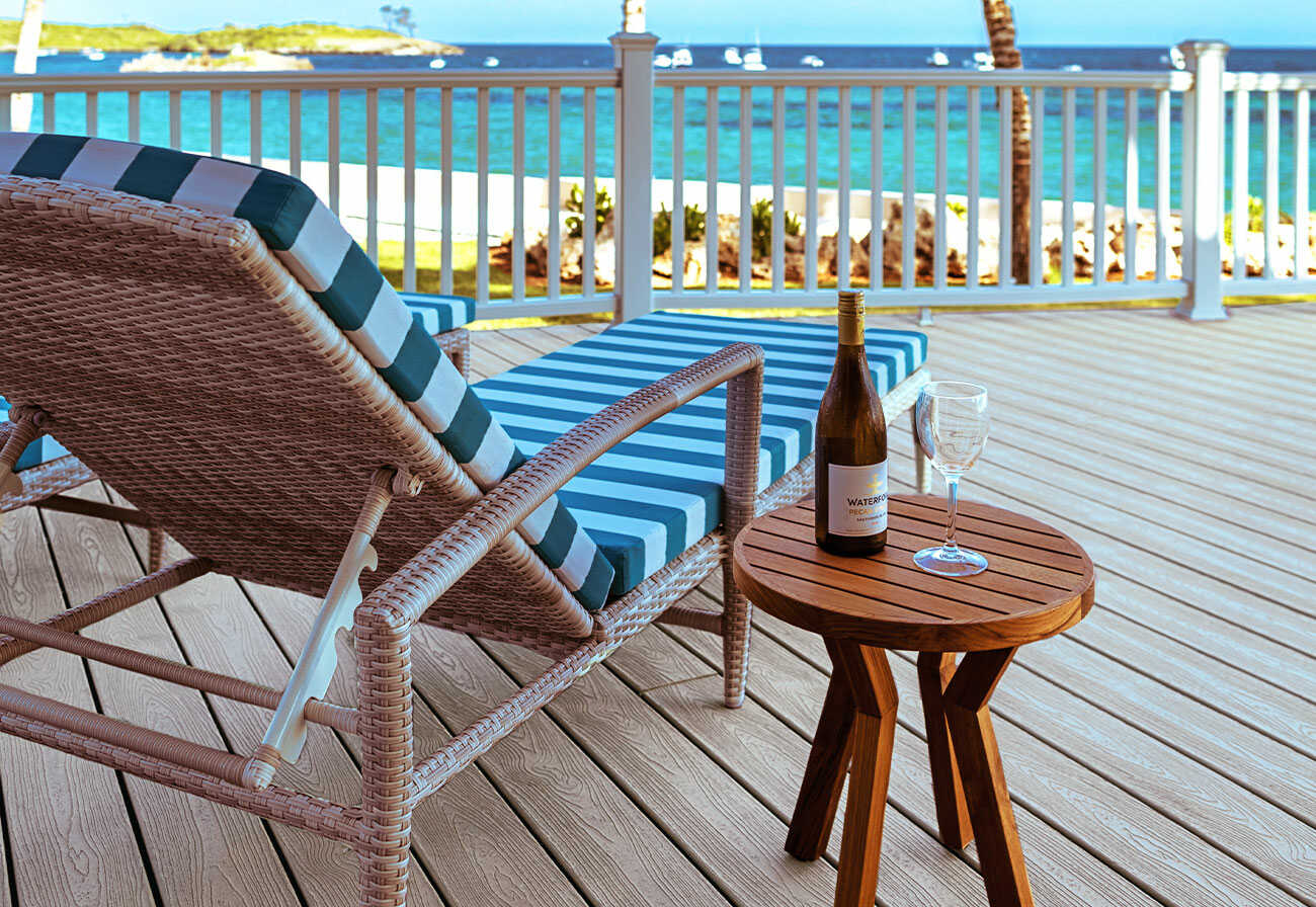 A sun lounge on a deck facing the nearby beach and ocean.