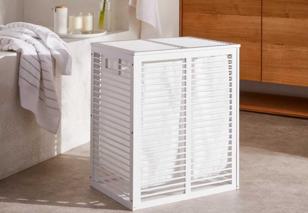 White wooden laundry unit in a bathroom next to a vanity.