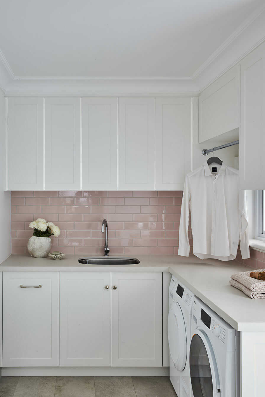 A laundry with pale pink subway tile splashback.