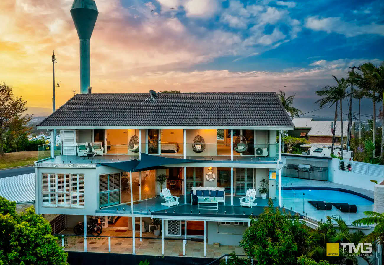 Rear view of a three-storey home with a pool.