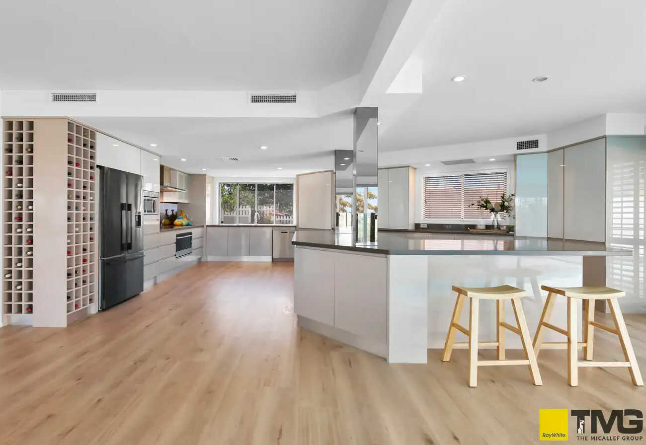 Large modern kitchen with mirror splashback and hug wine storage racks.