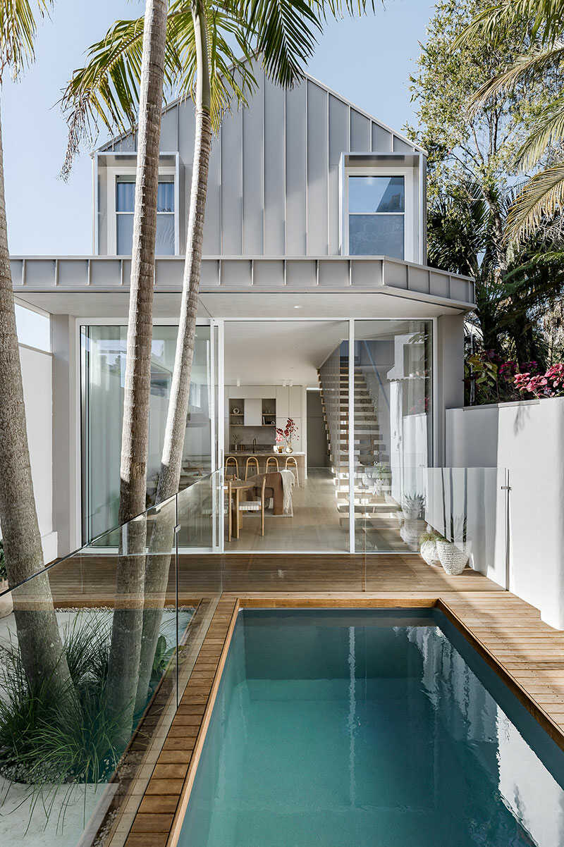 Small pool terrace of a town house with glass fencing and deck.