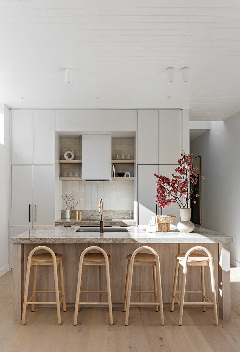 Renovated kitchen with four woodem stools and a thick marble bench.