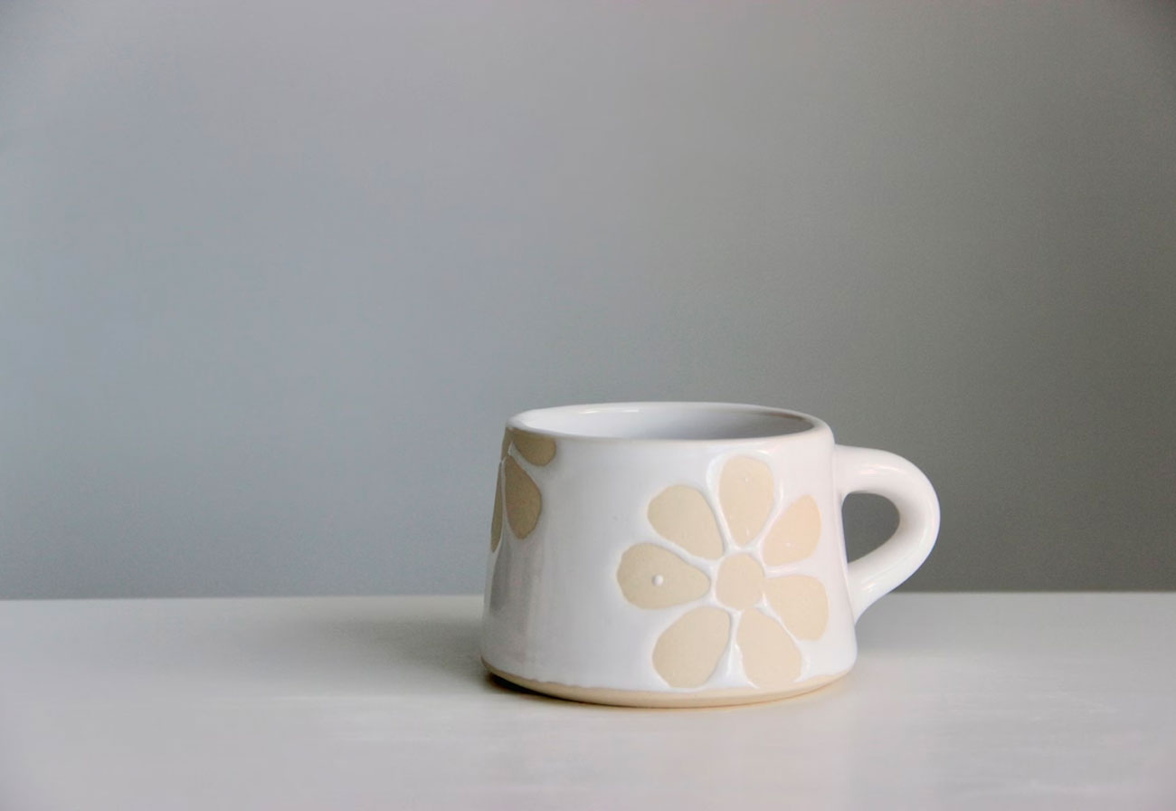 A daisy-themed mug on a bench.