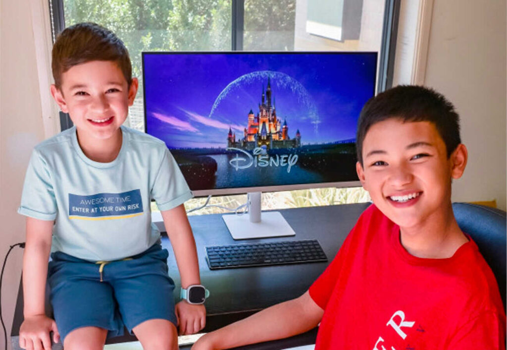 Smiling boys sitting in front of a smart monitor.