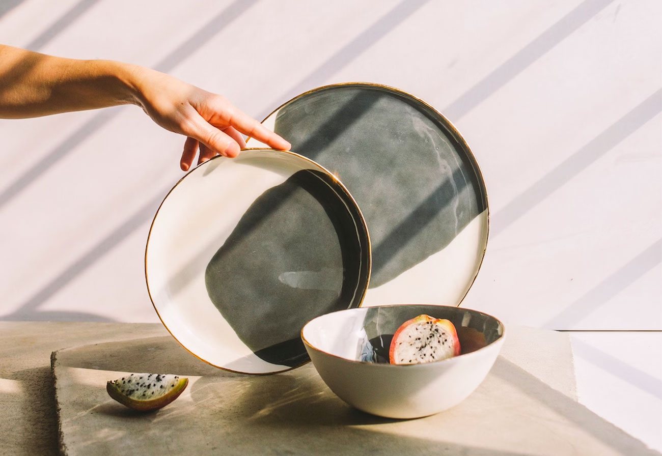 Hand touching a set of handmade dinner plates.