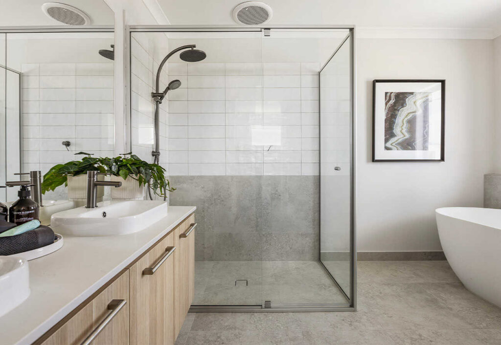 A modern bathroom with freestanding white bathtub and double vanity.