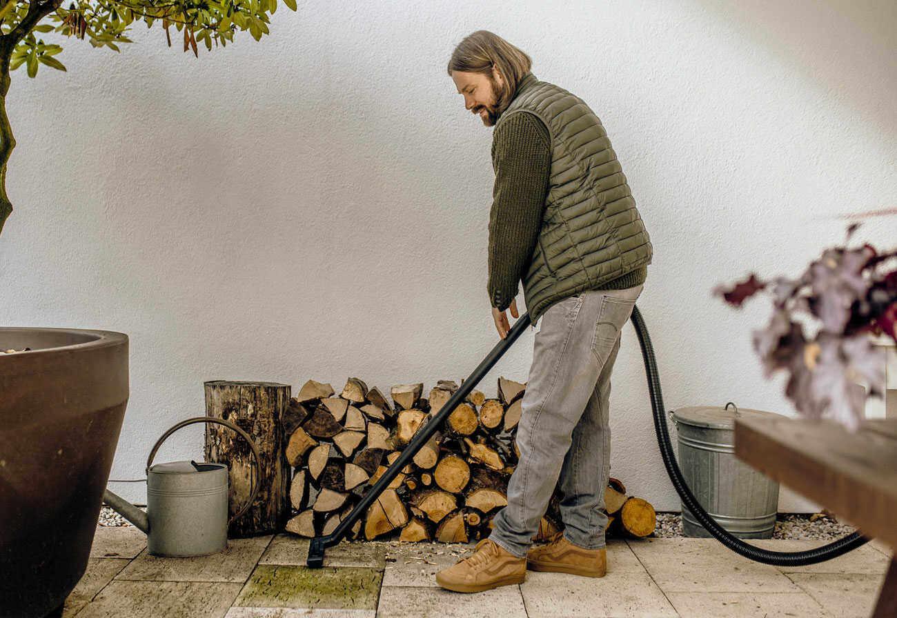 Man using a wet and dry vacuum cleaner outdoors.