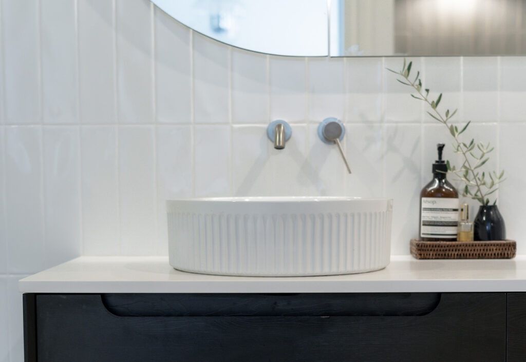 Vertical white gloss tiles on a bathroom wall.