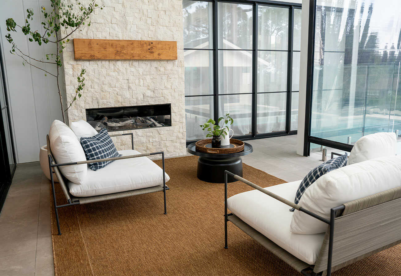 Covered alfresco area with armchairs, and an outdoor fireplace.