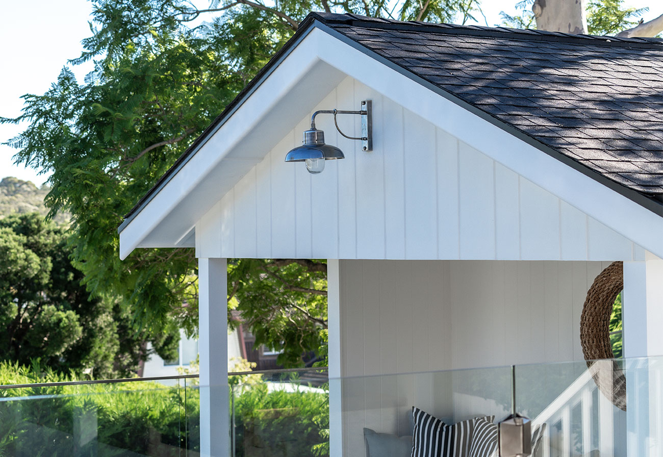 A modern pool house with a barn light mounted at the top.