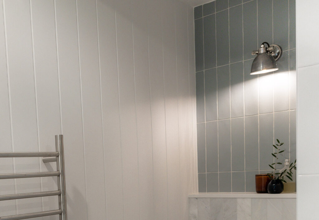 Antique silver wall light above a toilet shelf in a modern bathroom.