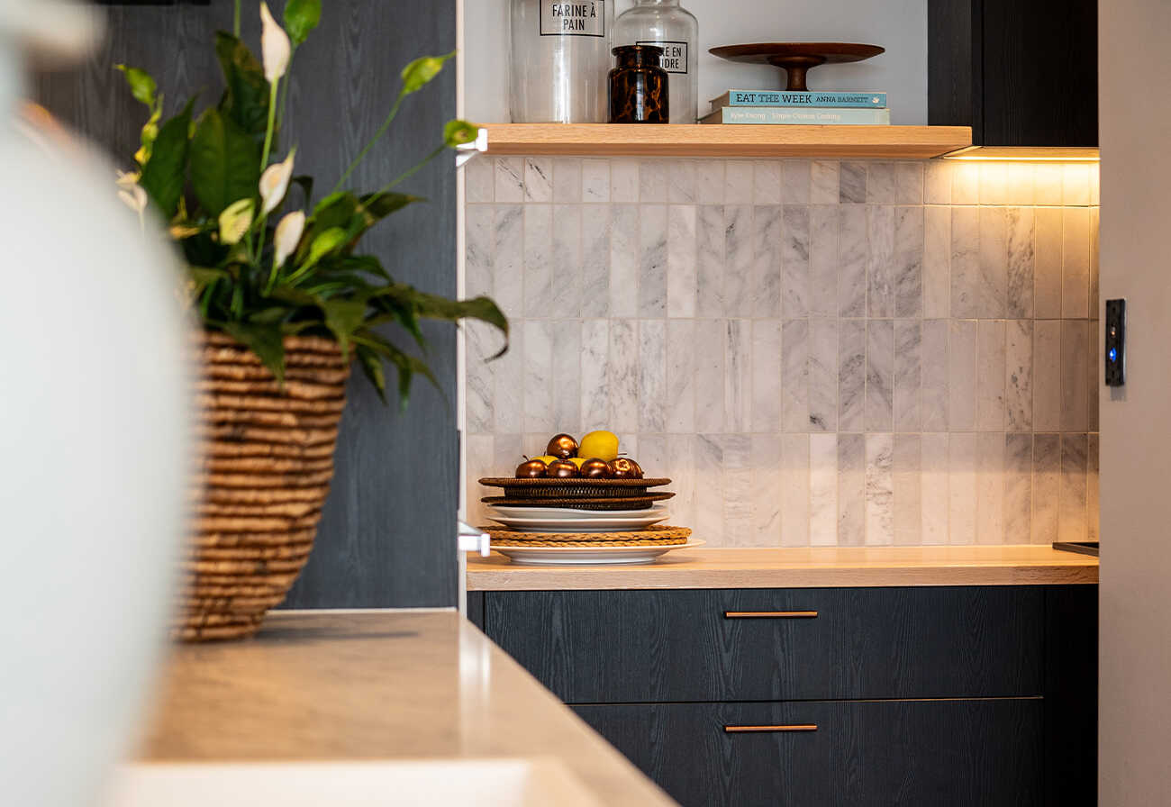 View into a butler's pantry with oak benchtops and black cabinets.