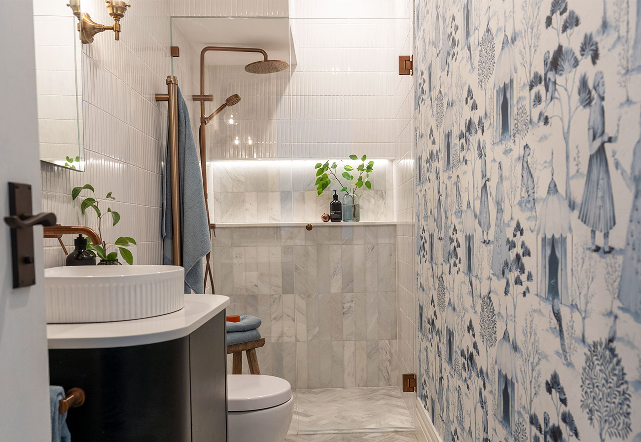 Modern guest bathroom with brushed copper tapware and blue wallpaper.