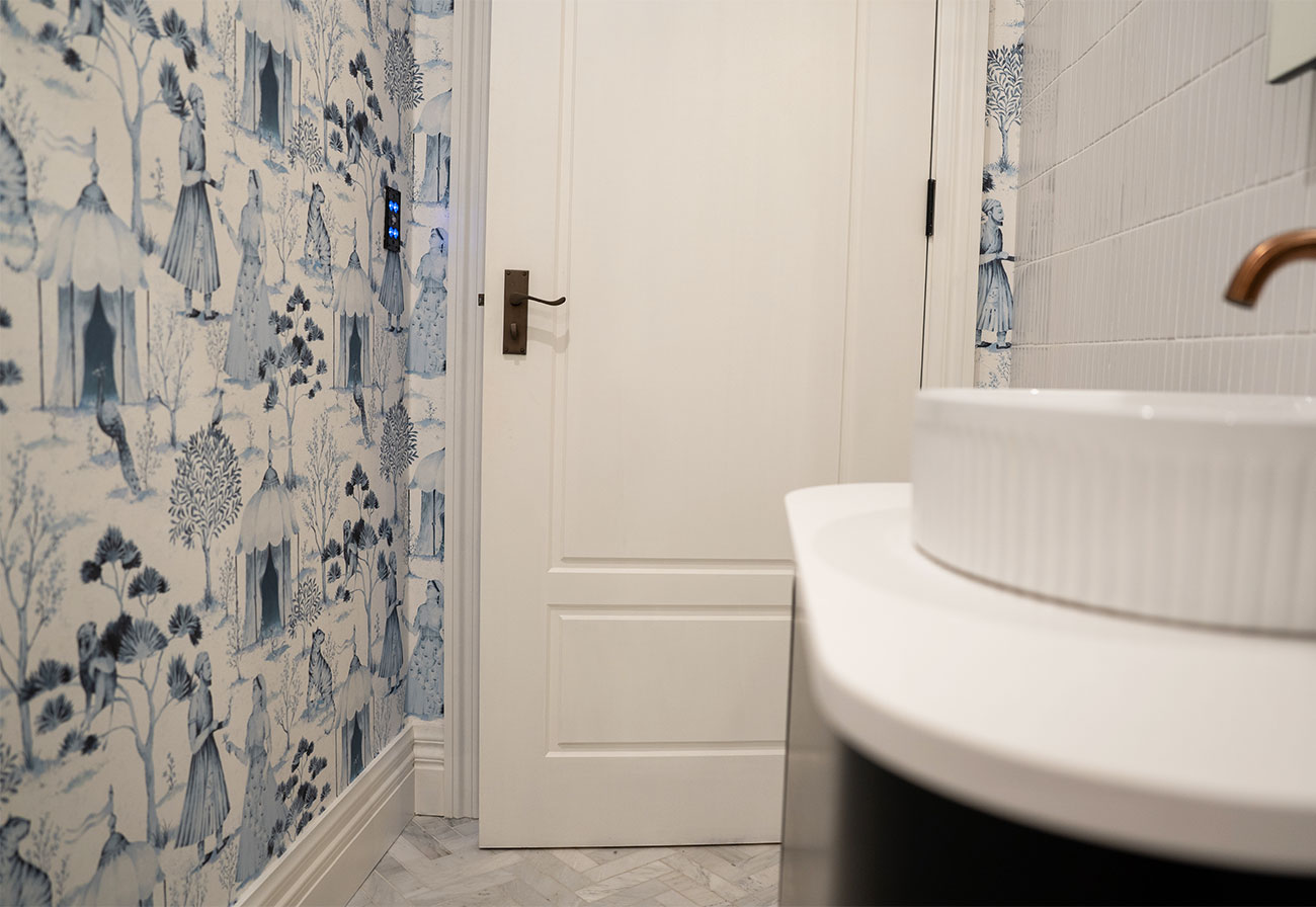 Bathroom wall featuring blue patterned wallpaper.