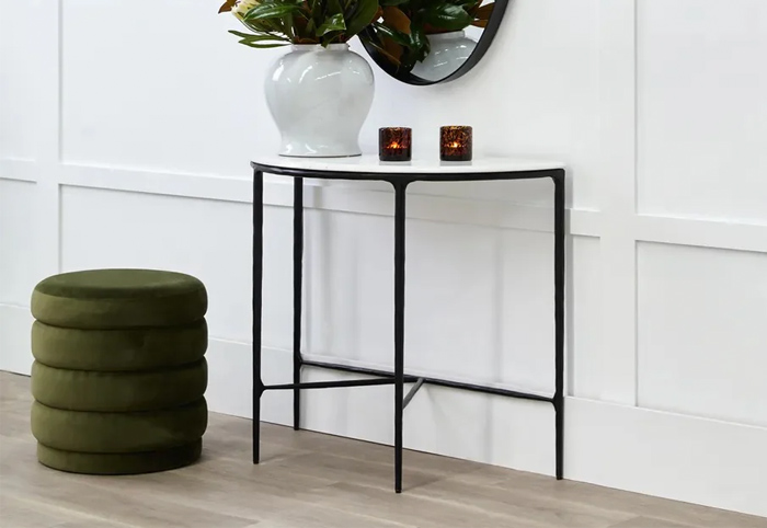 Curved marble-top console table next to a green ottoman.