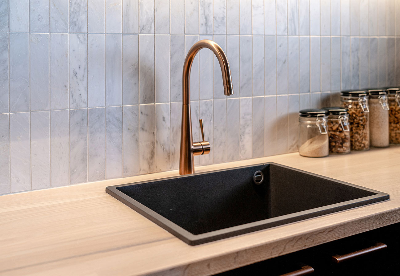 Black granite sink and copper tap in a butler's pantry.