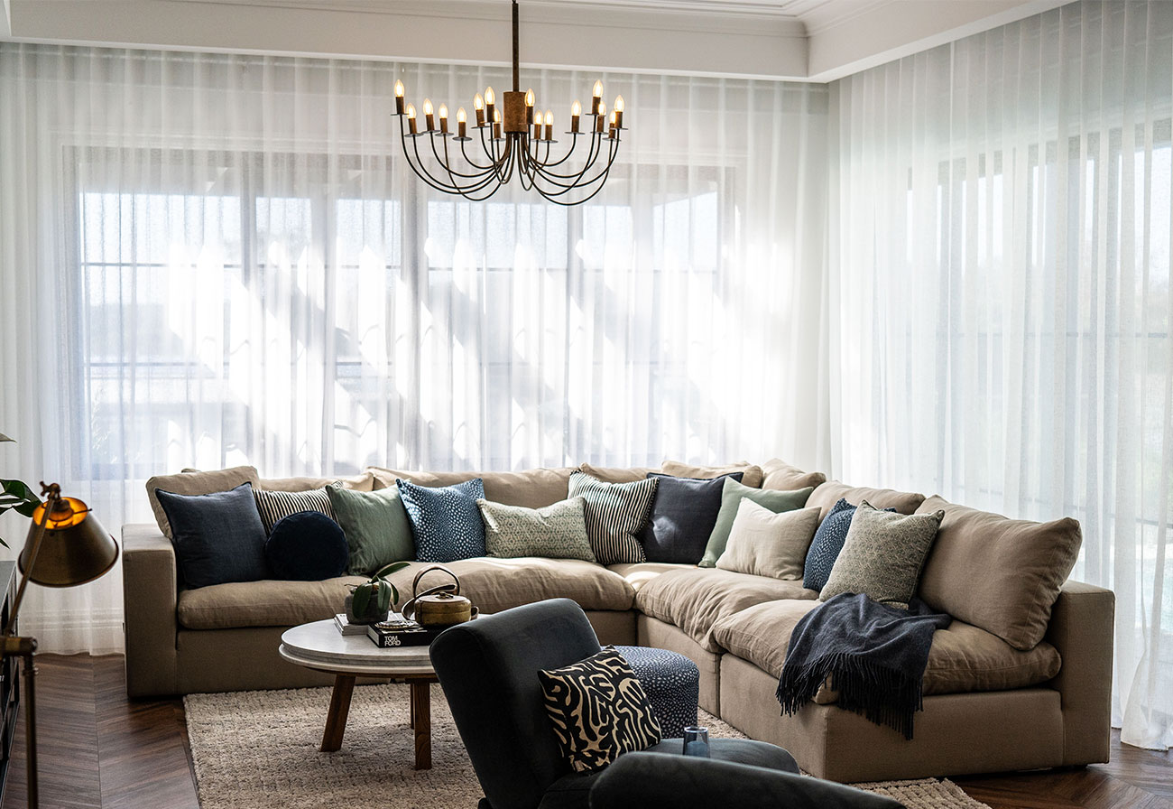 Living room with sheer curtains and corner sofa.