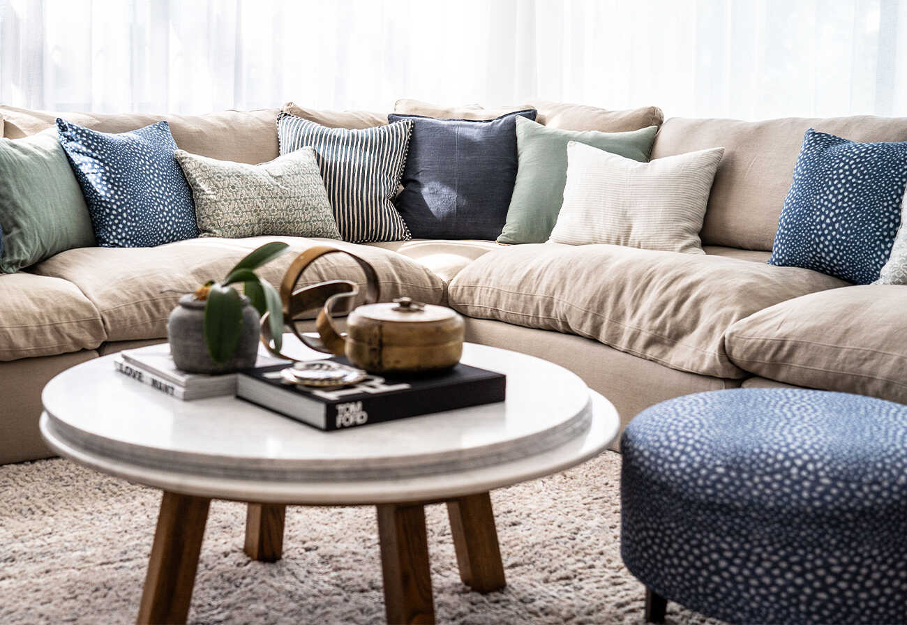 Curved beige couch with assorted cushion.