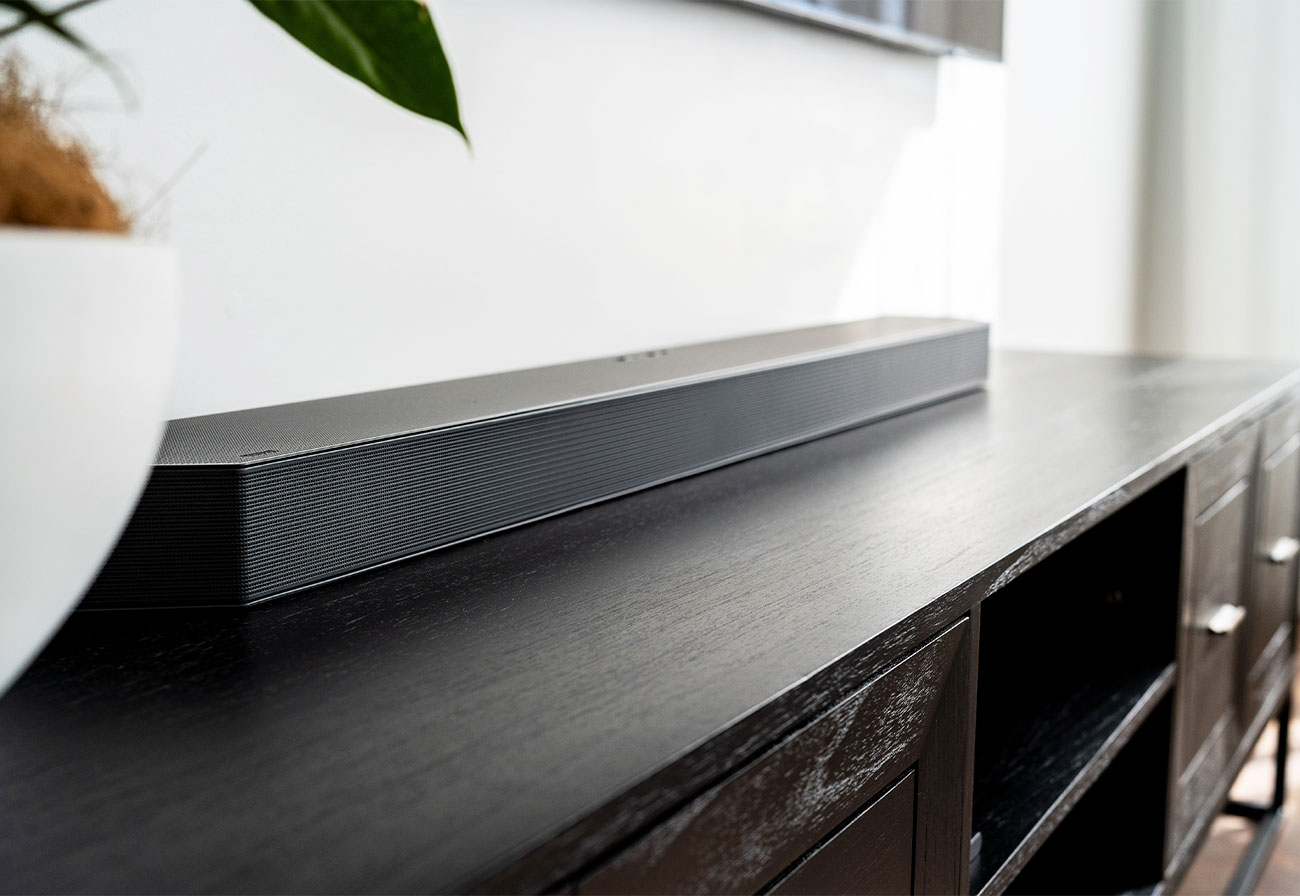 Samsung sound bar on top of a walnut entertainment unit.