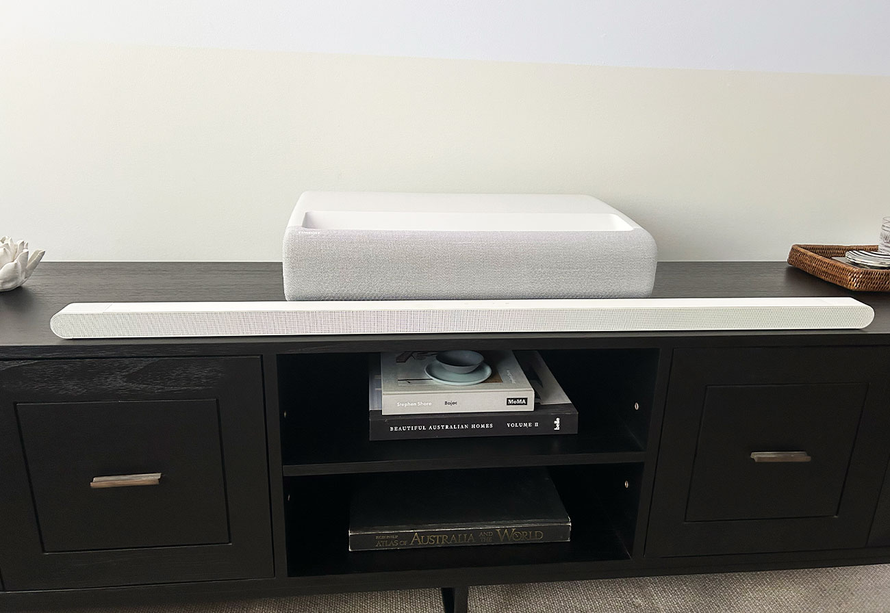 Samsung projector and soundbar on a dark timber entertainment unit.