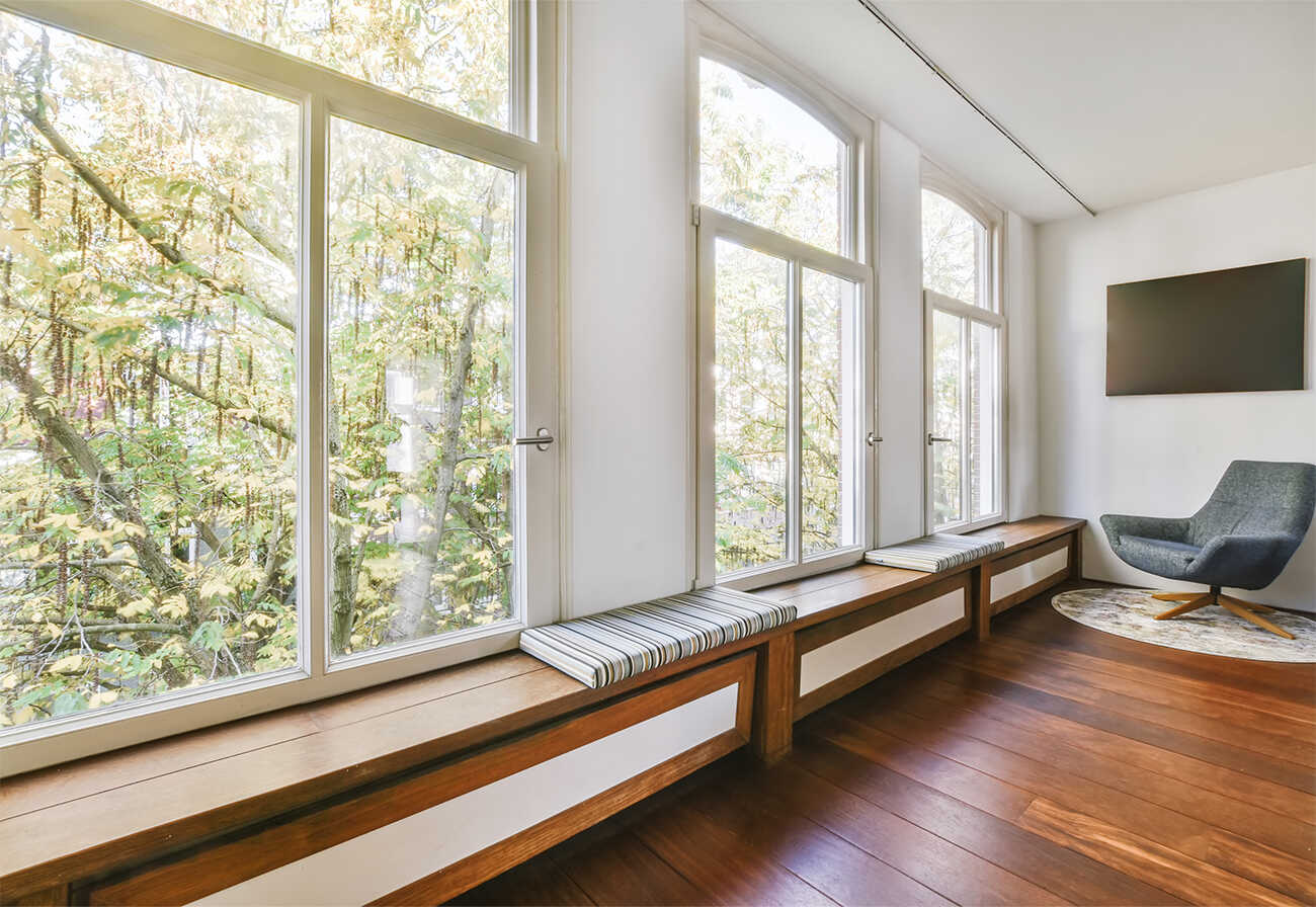 Room with large windows overlooking greenery. 