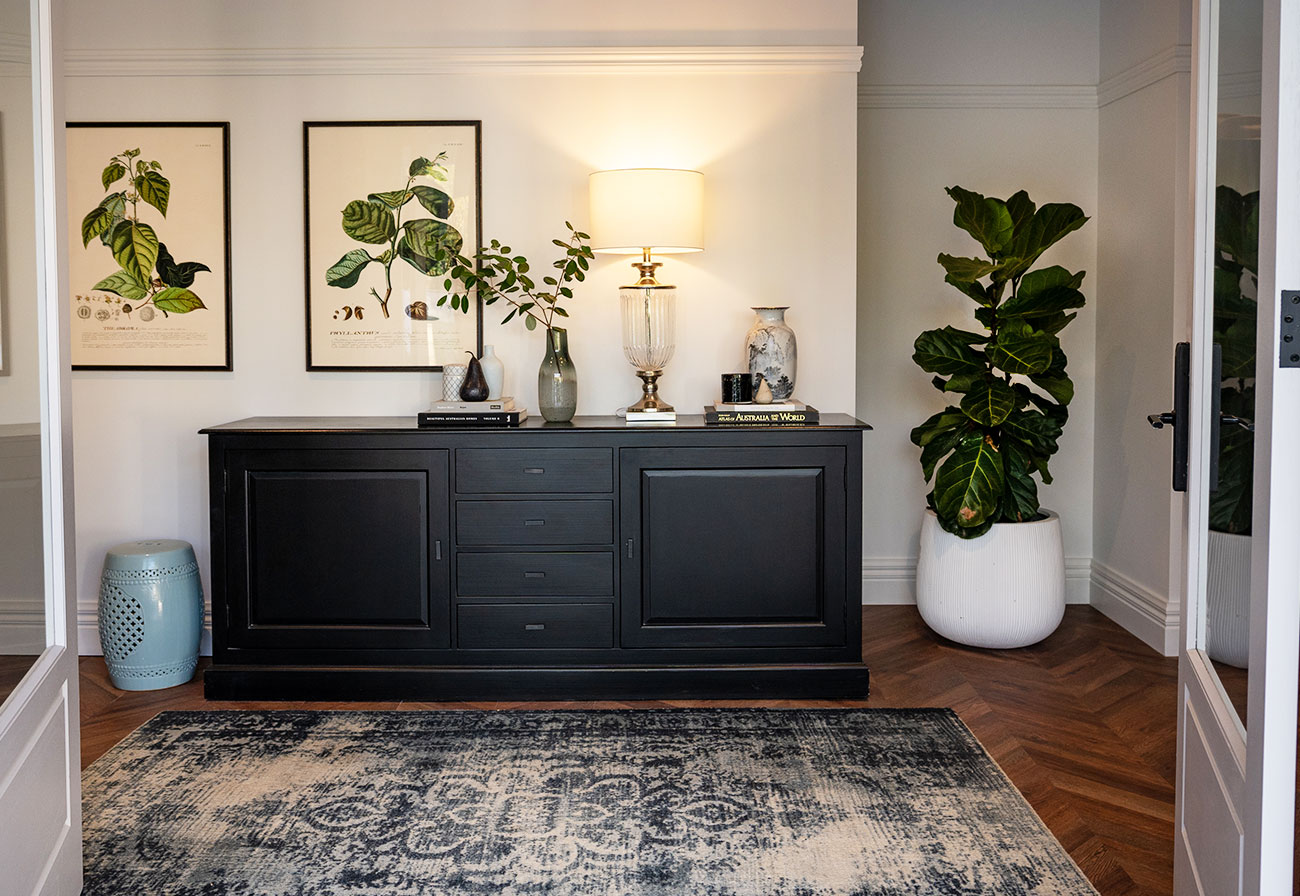 Modern Farmhouse entrance with black chest and floral wall prints.