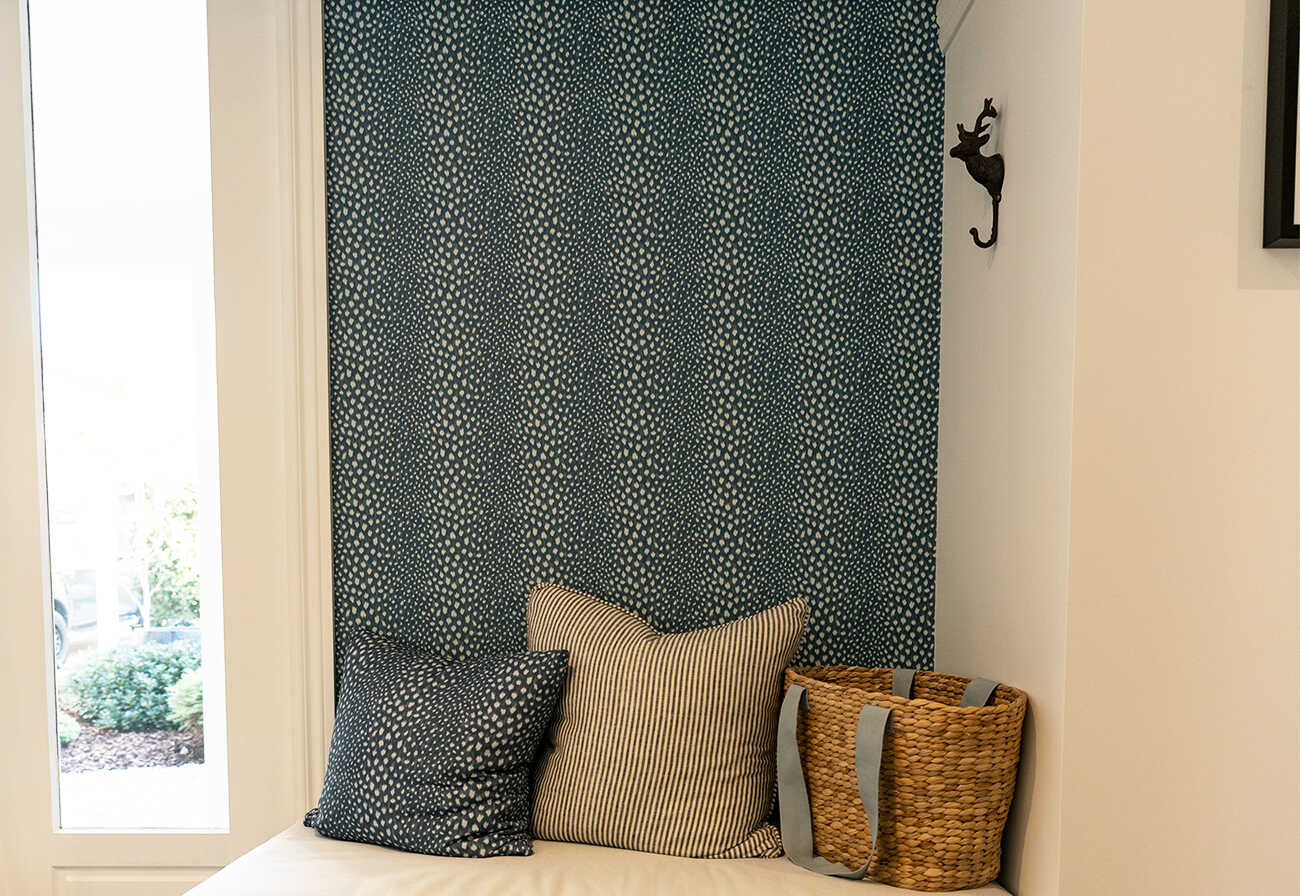 Blue patterned wallpaper above a bench seat in a home's entrance.