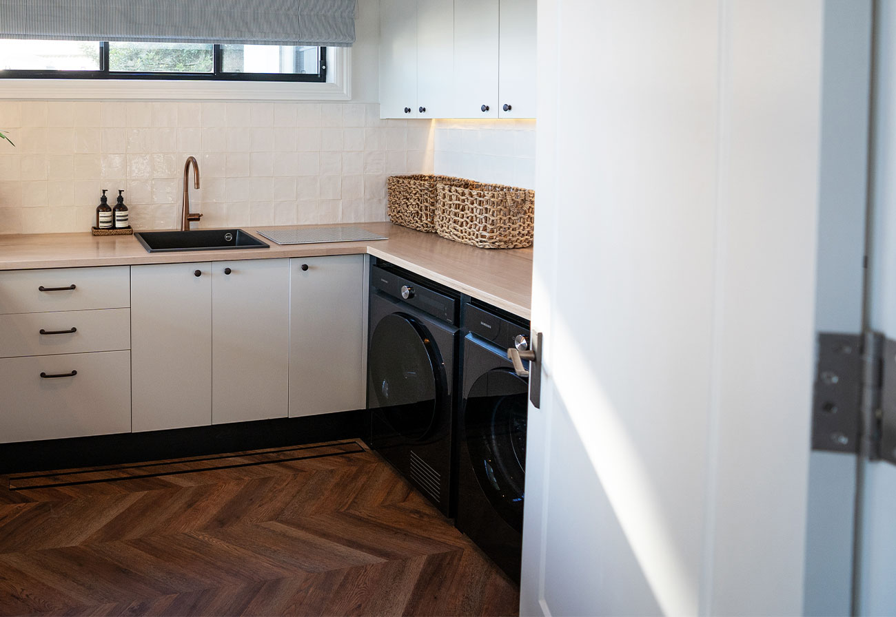 Modern Farmhouse laundry with black Samsung appliances under an oak bench.