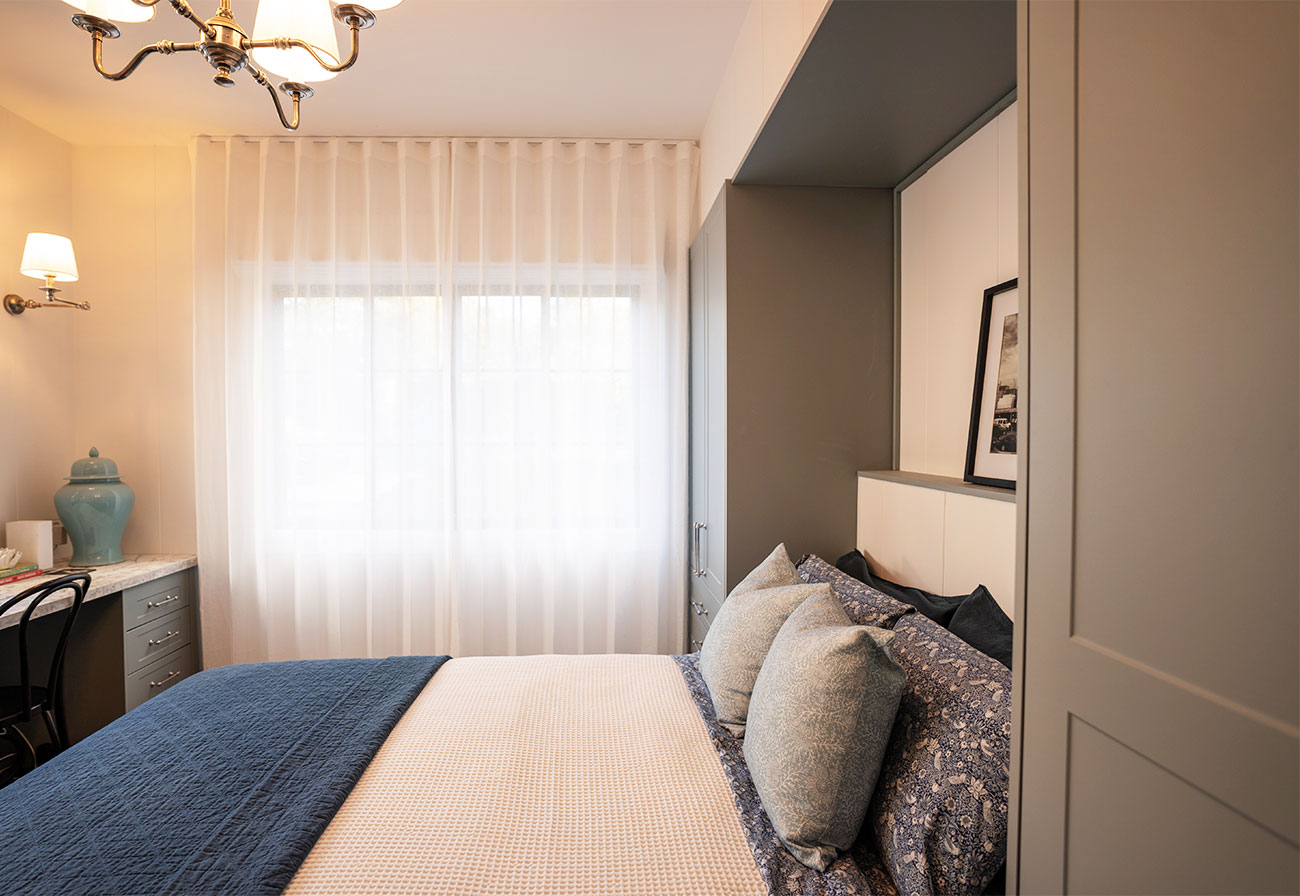 Guest bedroom with sheer curtains and sage cabinetry.