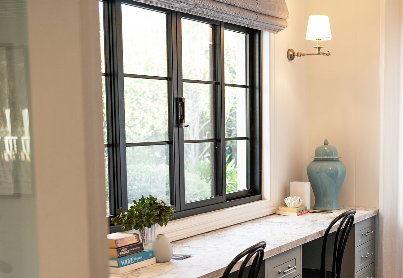 Marble-look desk under a large window with two workspaces.