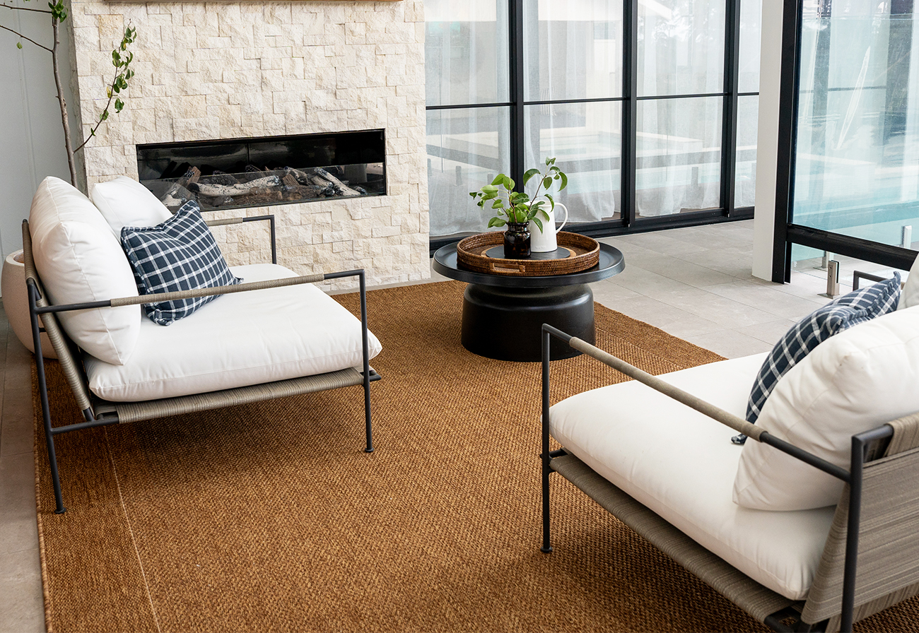 Alfresco area with outdoor fireplace and armchairs.