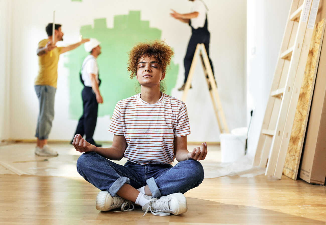 Woman doing yoga amidst renovation activity.