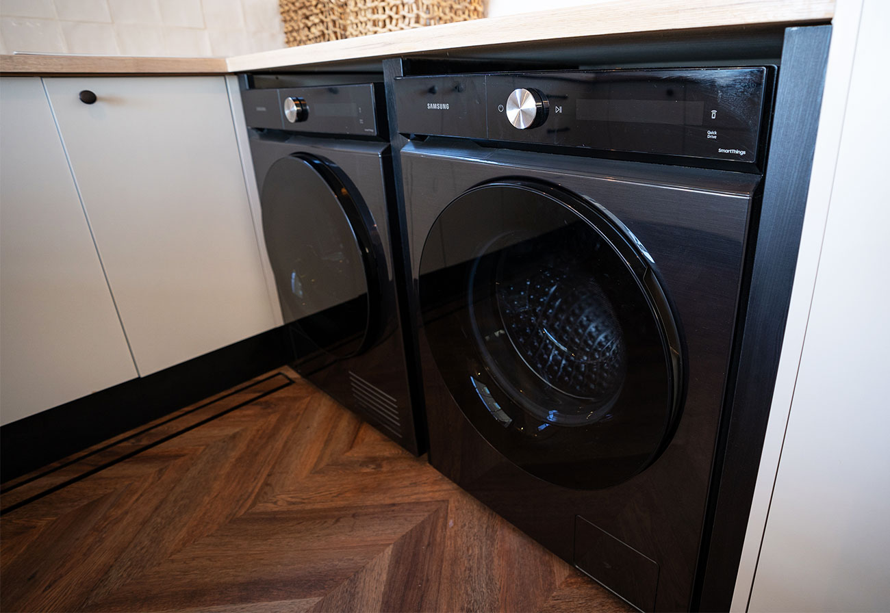 Black Samsung laundry appliances under an oak benchtop.