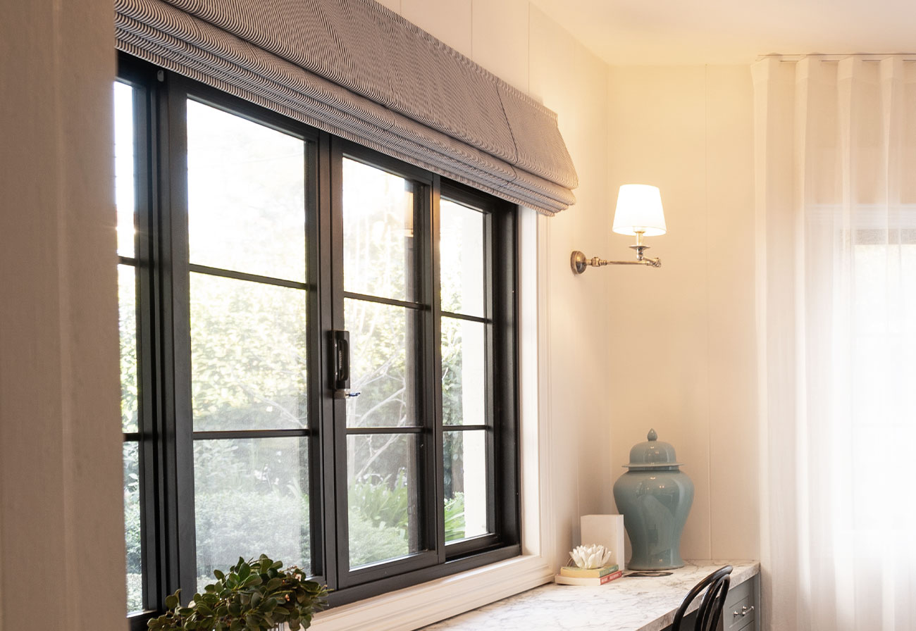 Blue roman blinds above a long built-in desk.