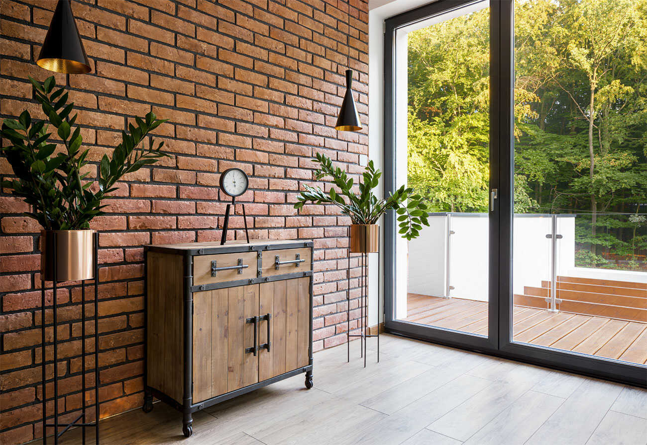 Exposed brick wall next to an entryway with glass doors.