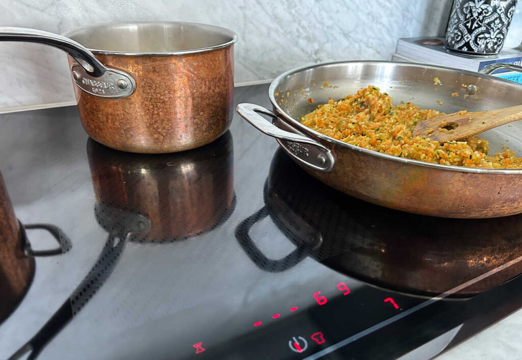 Pan of risotto cooking on a black induction cooktop.