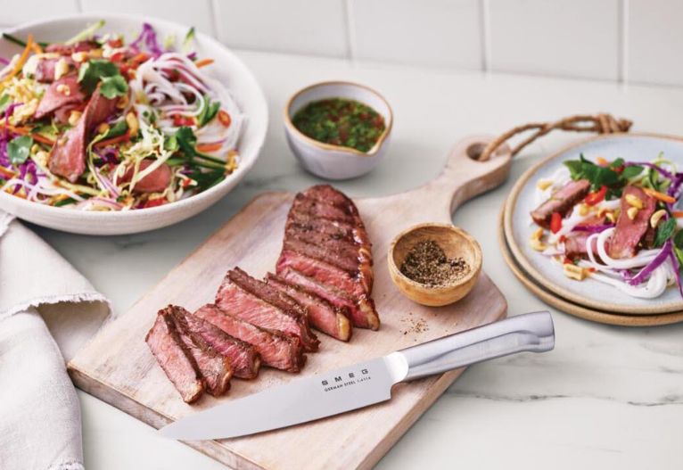 Sliced meat on a board with a SMEG knife.