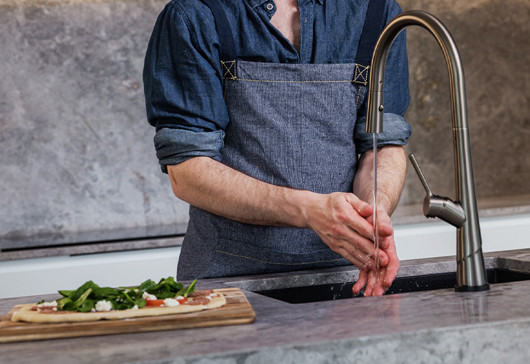 Man washes hands at a kitchen sink.