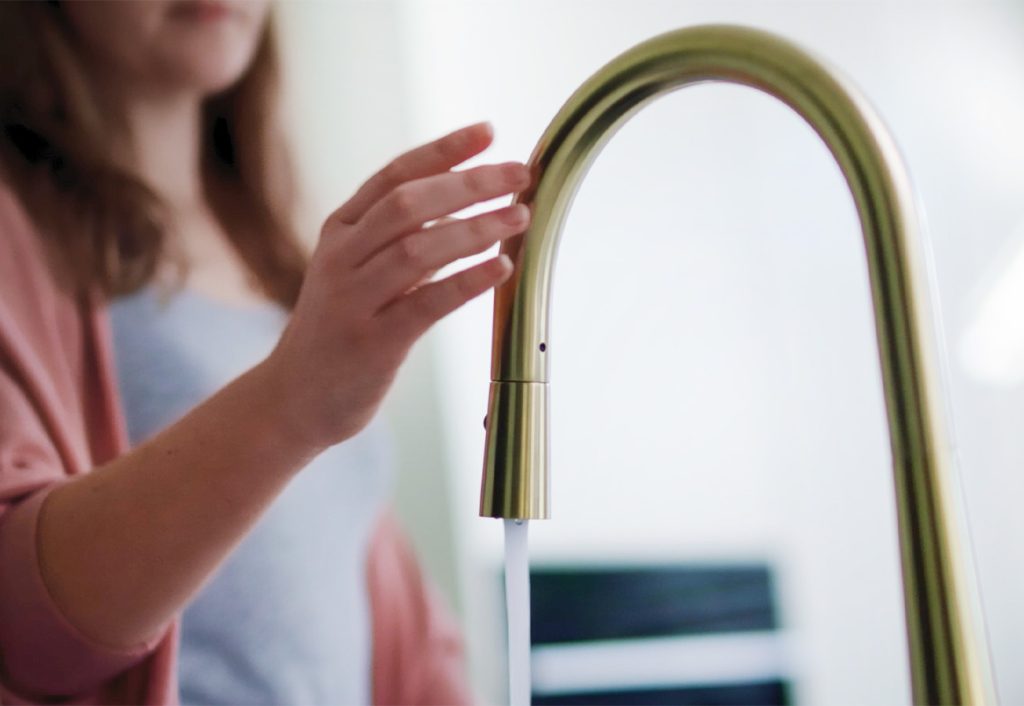 Woman touching a kitchen tap to turn it off.