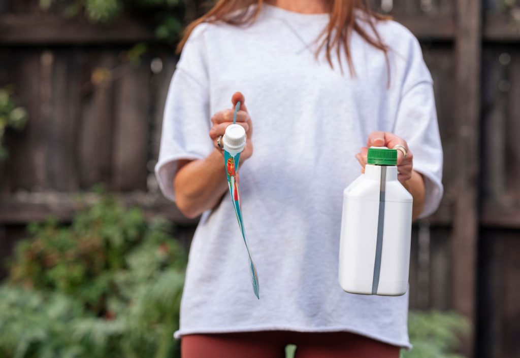 Woman holding two types of plant food packaging.